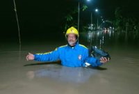 Seorang petugas Taruna Siaga Bencana sedang berjalan di antara genangan air yang menutup jalan di wilayah Kecamatan Pilangkenceng, Kabupaten Madiun, Jawa Timur. Foto: Ist
