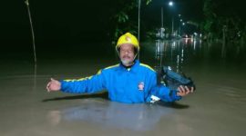 Seorang petugas Taruna Siaga Bencana sedang berjalan di antara genangan air yang menutup jalan di wilayah Kecamatan Pilangkenceng, Kabupaten Madiun, Jawa Timur. Foto: Ist