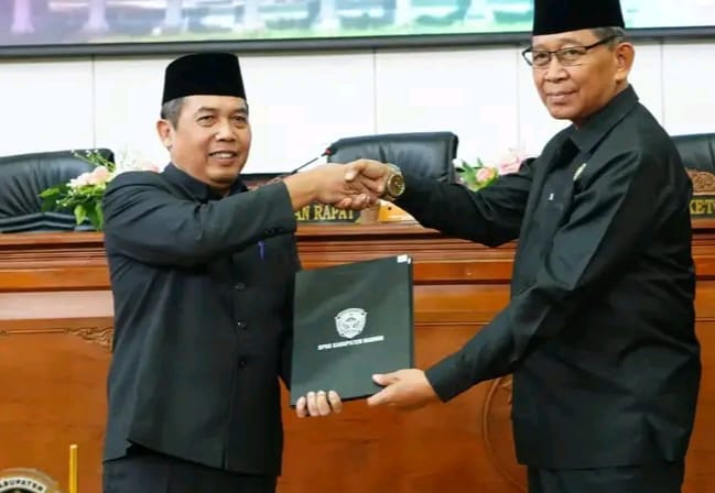 Pj. Bupati Madiun Tontro Pahlwanto (kiri) dan Wakil Ketua DPRD Kabupaten Madiun Slamet Rijadi menunjukkan bukti kesepakatan dalam sidang paripurna, Rabu (7/8/2024).