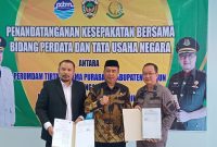 Bupati Madiun Hari Wuryanto (tengah), Kajari Madiun Ocktario Hartawan Putra (kanan), dan Direktur Utama PDAM Kabupaten Madiun Imansyah menunjukkan dokumen kesepakatan bersama yang telah ditandatangani, Kamis (10/7/2025). 