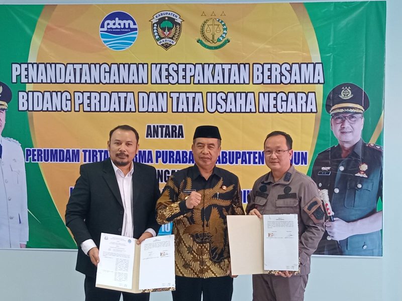 Bupati Madiun Hari Wuryanto (tengah), Kajari Madiun Ocktario Hartawan Putra (kanan), dan Direktur Utama PDAM Kabupaten Madiun Imansyah menunjukkan dokumen kesepakatan bersama yang telah ditandatangani, Kamis (10/7/2025). 