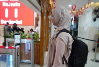 Seorang calon penumpang KA sedang di scan pengenalan wajah untuk percepat boarding penumpang di stasiun Madiun. 