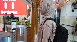 Seorang calon penumpang KA sedang di scan pengenalan wajah untuk percepat boarding penumpang di stasiun Madiun. 