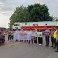 Personel KAI Daop 7 Madiun bentangkan banner saat sosialisasi keselamatan di pintu pelintasan Stasiun Madiun, Jumat (15/8/2025).