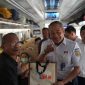 Vice President Daop 7 Madiun, Suharjono, membagikan souvenir kepada pelanggan kereta api. Foto : Humas Daop 7 Madiun