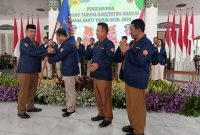 Bupati Madiun Hari Wuryanto menyerahkan pataka kepada Ketua Karang Taruna Kabupaten Madiun periode 2025-2030.
