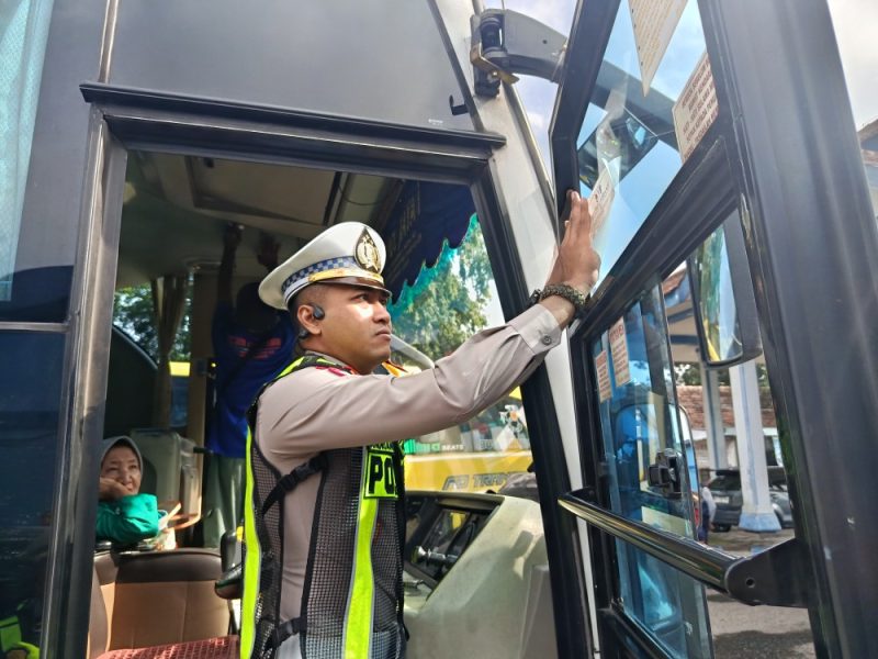 Kasat Lantas Polres Madiun, AKP Andrian Permana menempelkan stiker di sebuah bus yang sudah lolos RAM Check di terminal Caruban, Rabu (11/2/2026). 